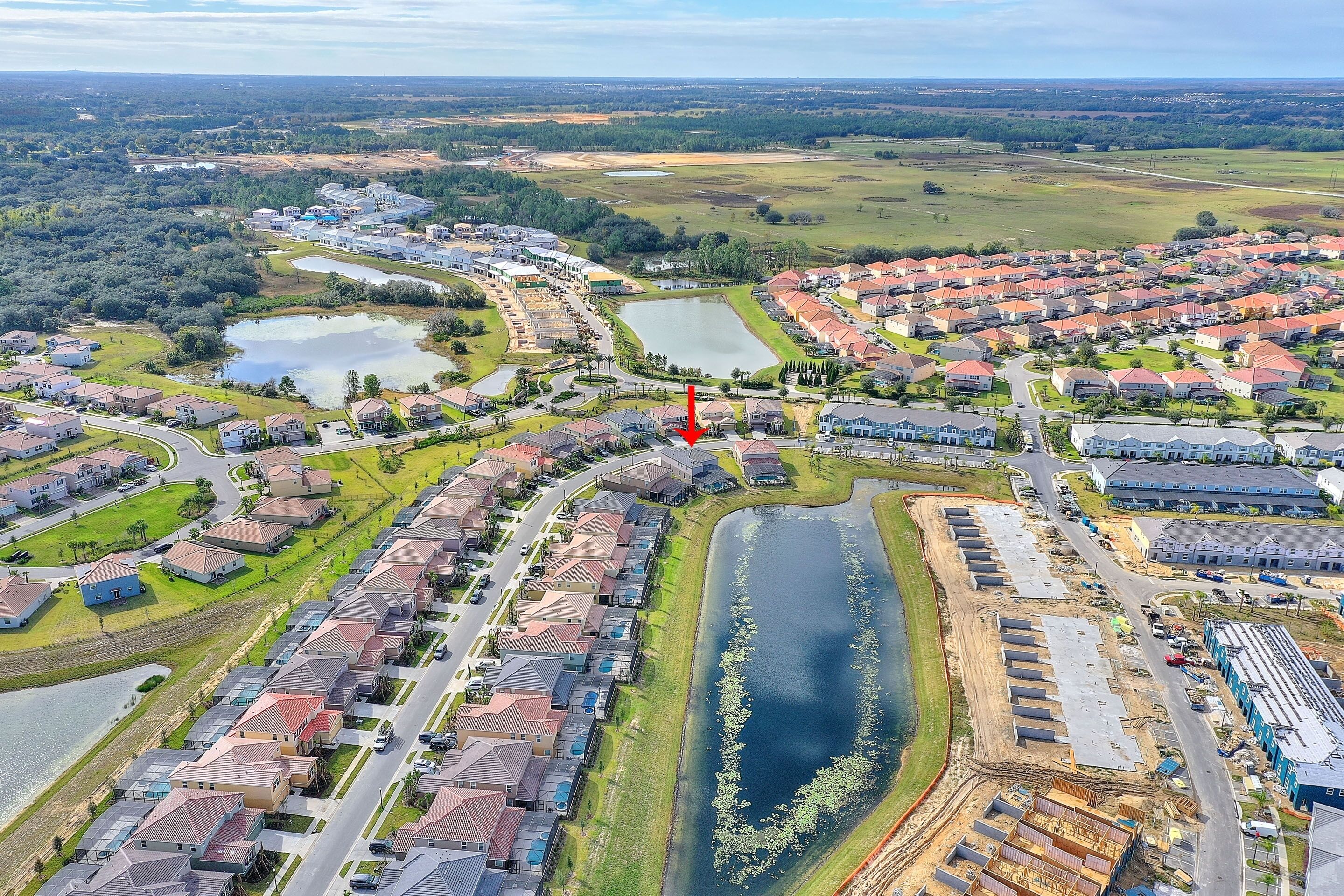 Vue aérienne d’un quartier résidentiel avec des maisons, un lac et un chantier de construction.
