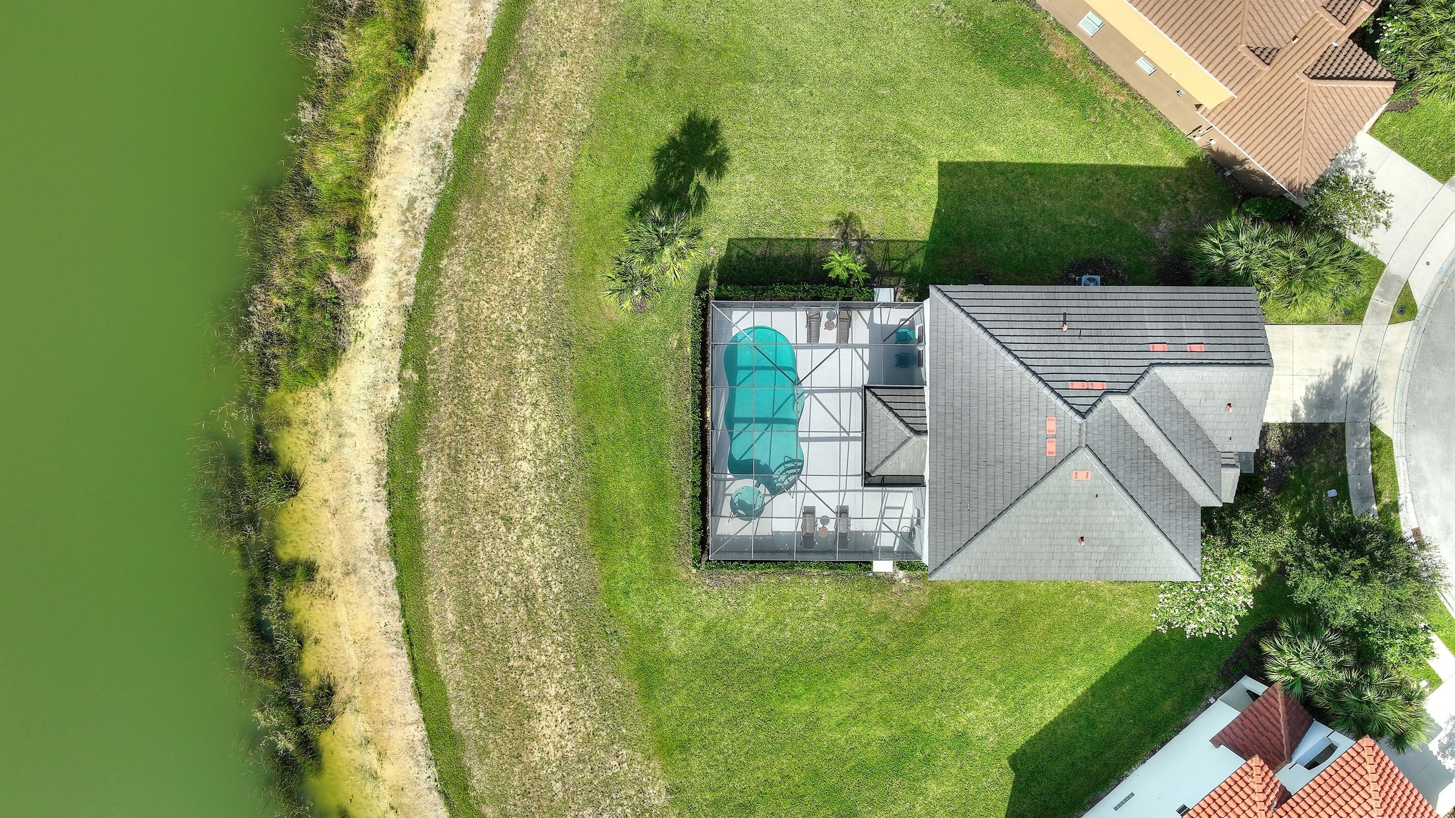 Vista aérea de una casa con piscina, terraza cubierta y patio cercado.