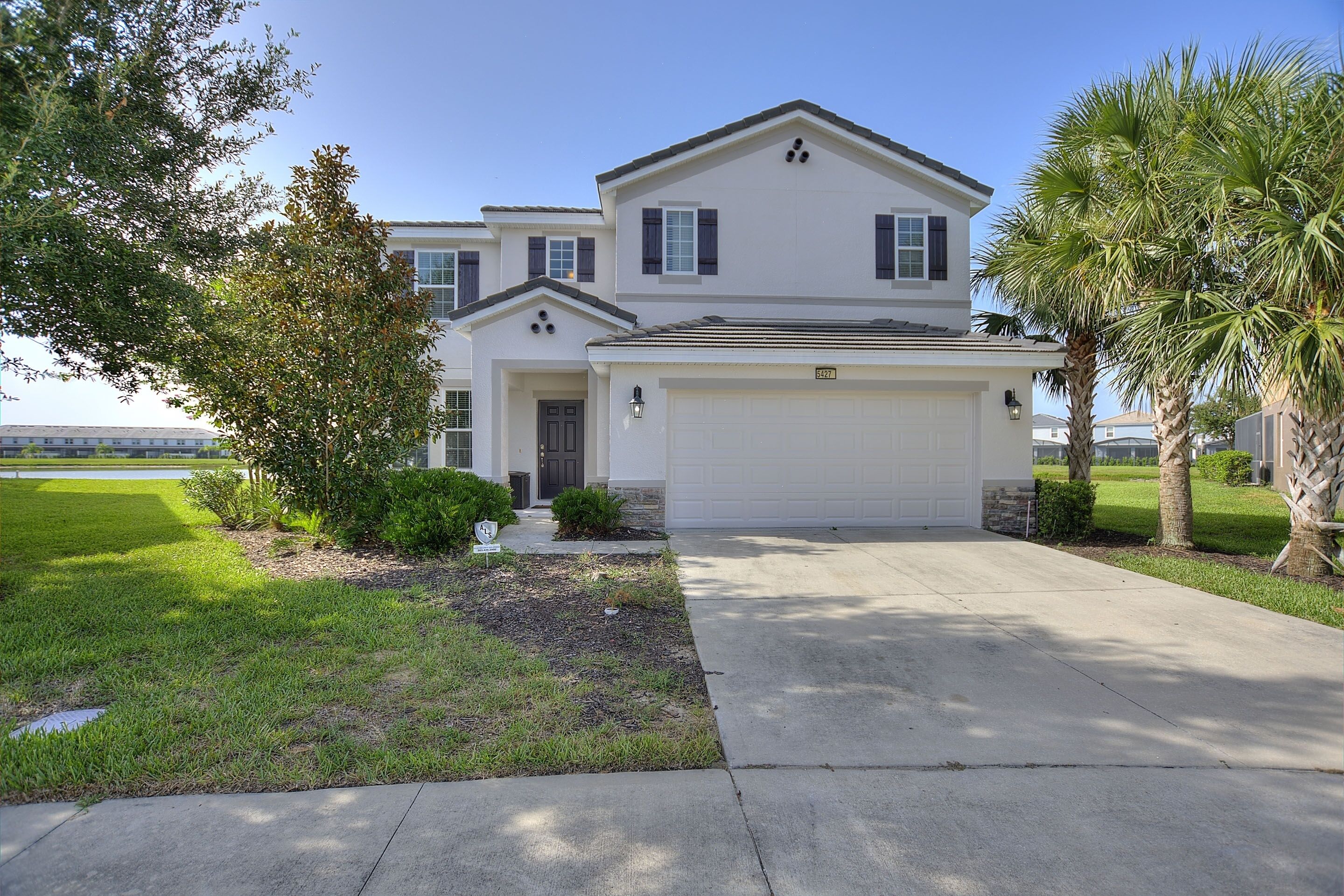 A two-story house with a white exterior, a garage, and a well-maintained lawn.
