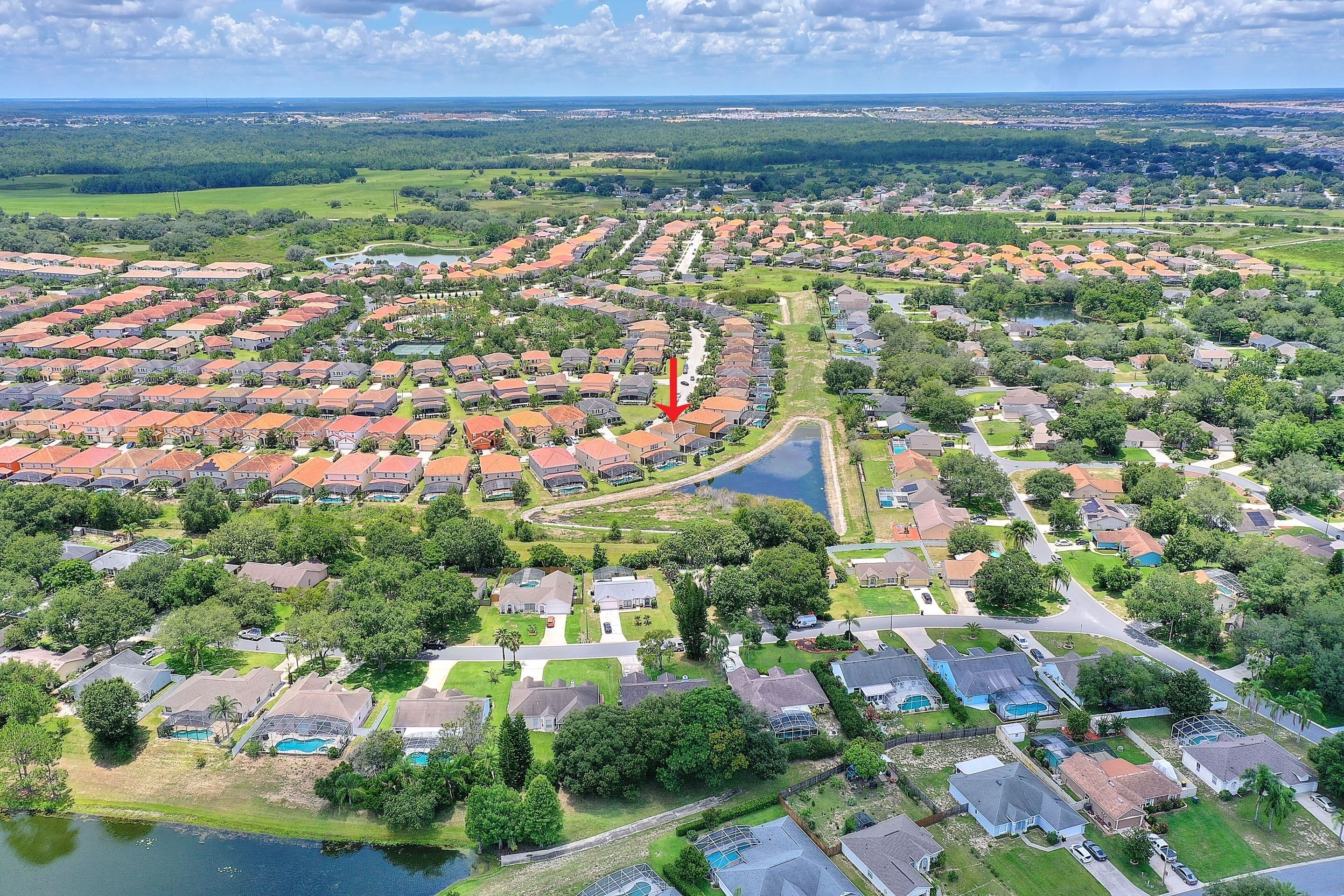 An aerial view of a residential area with houses, roads, and a body of water.