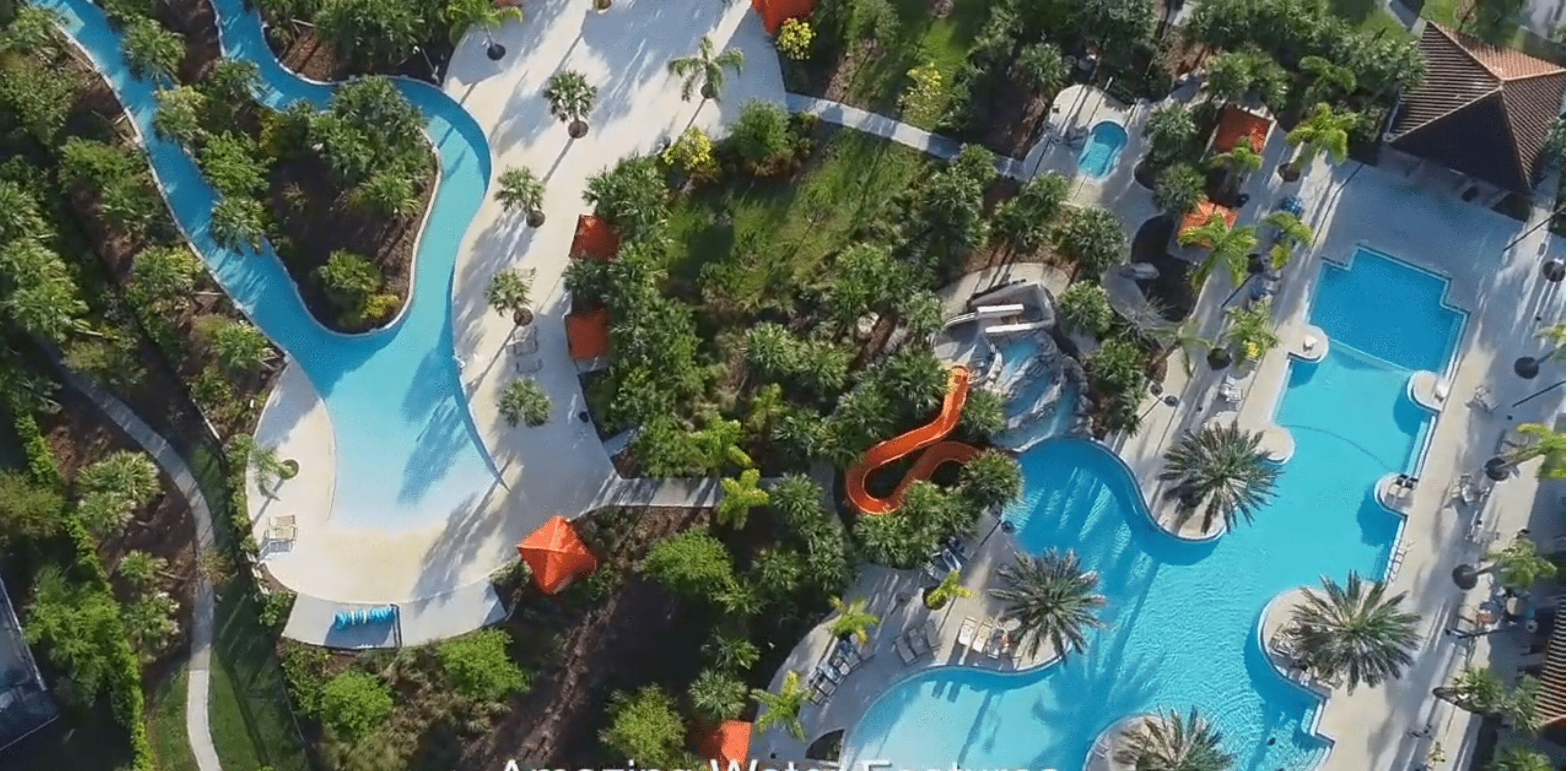 Eine Vogelperspektive zeigt einen luxuriösen Urlaubsort mit einem großen Pool, Wasserrutschen und üppiger Bepflanzung.