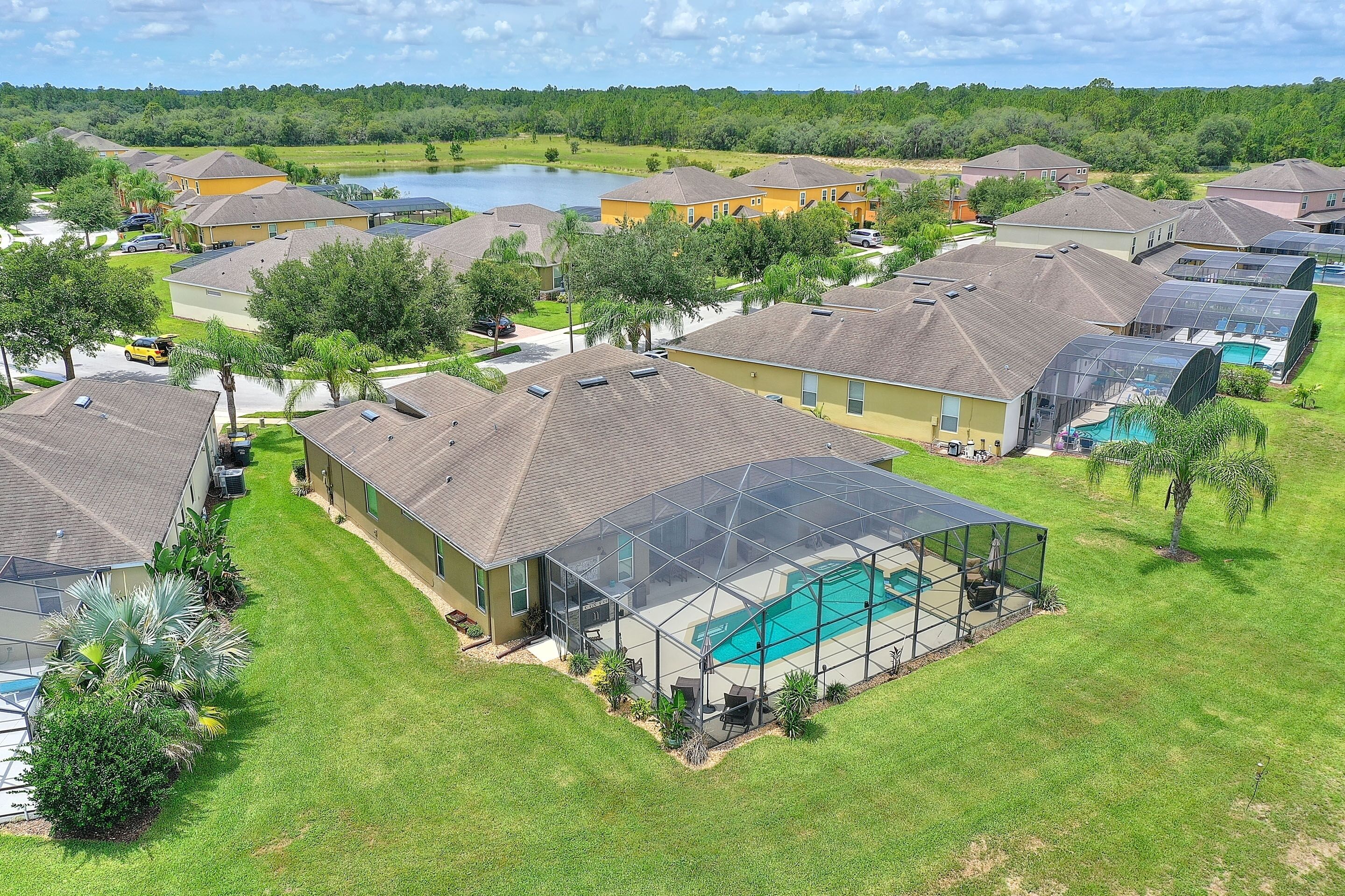 A residential area with houses, a swimming pool, and a lake in the background.