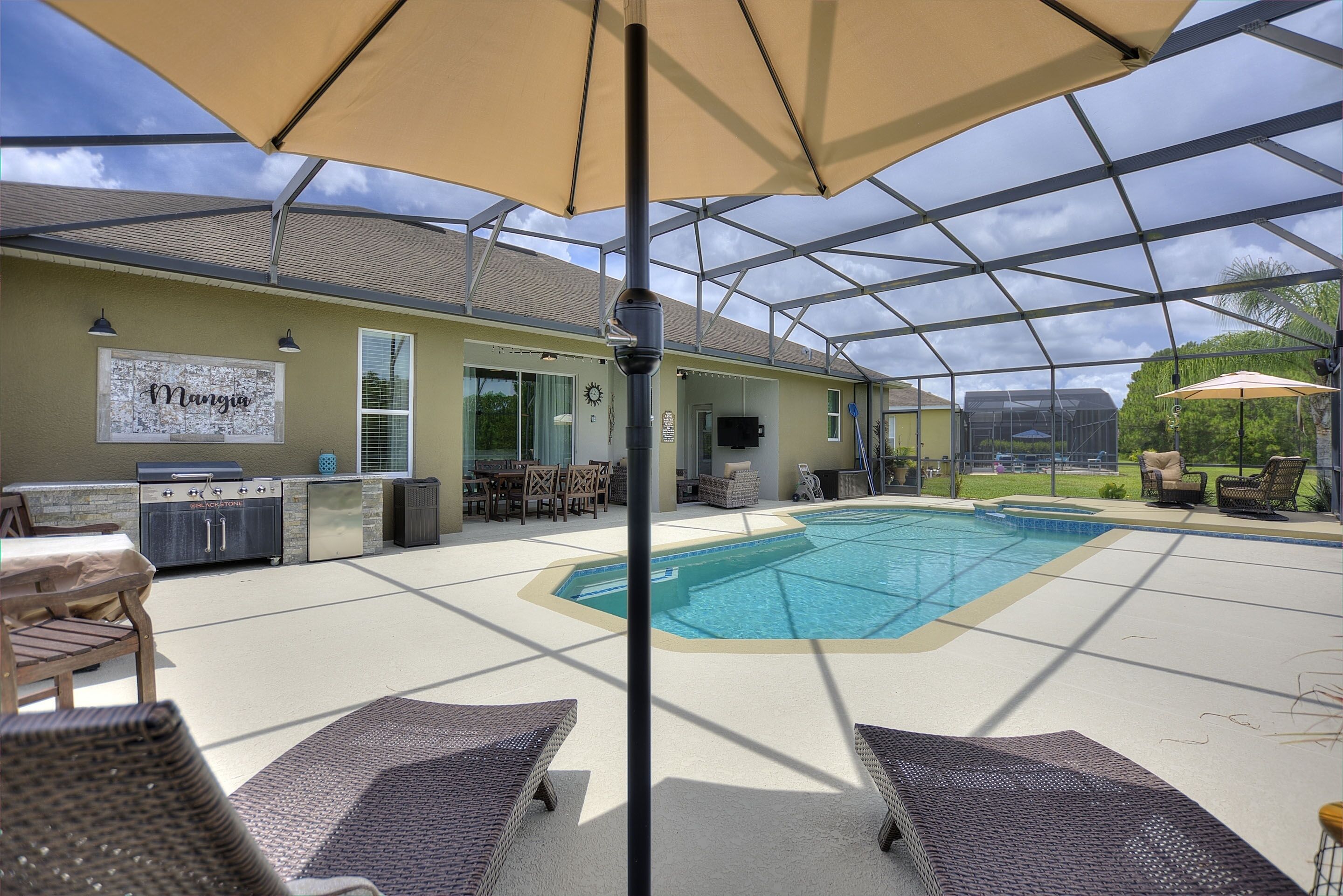 Un espace extérieur abrité comprenant une piscine, des chaises longues et un barbecue.