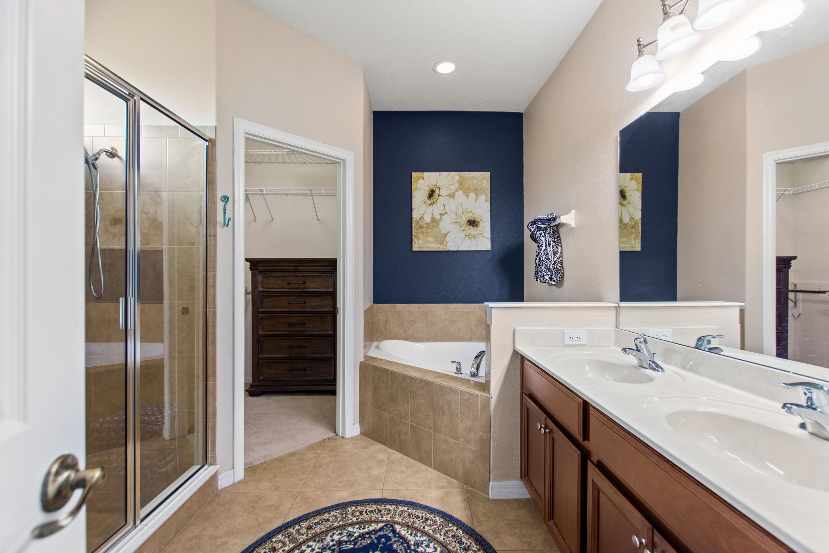 A bathroom with a glass shower enclosure, a bathtub, and a double sink vanity.