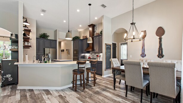 A spacious kitchen with a central island, dark wooden cabinets, and pendant lighting. - Serenity Now By Shine Villas At Watersong #416 5 Bedroom Villa (Davenport)