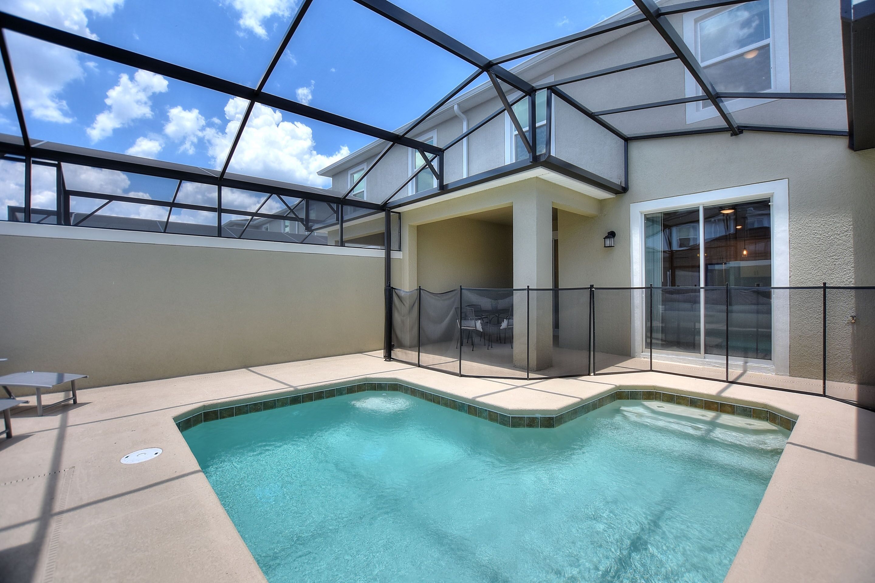 An indoor swimming pool with a glass ceiling, a covered patio area, and a view of the sky.