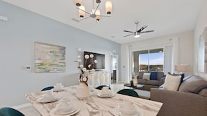 A modern living room with a marble dining table set for tea, a sofa, and a ceiling fan. - Edgewater Escape At Storey Lake By Shine Villas 2 Bedroom Apts (Kissimmee)