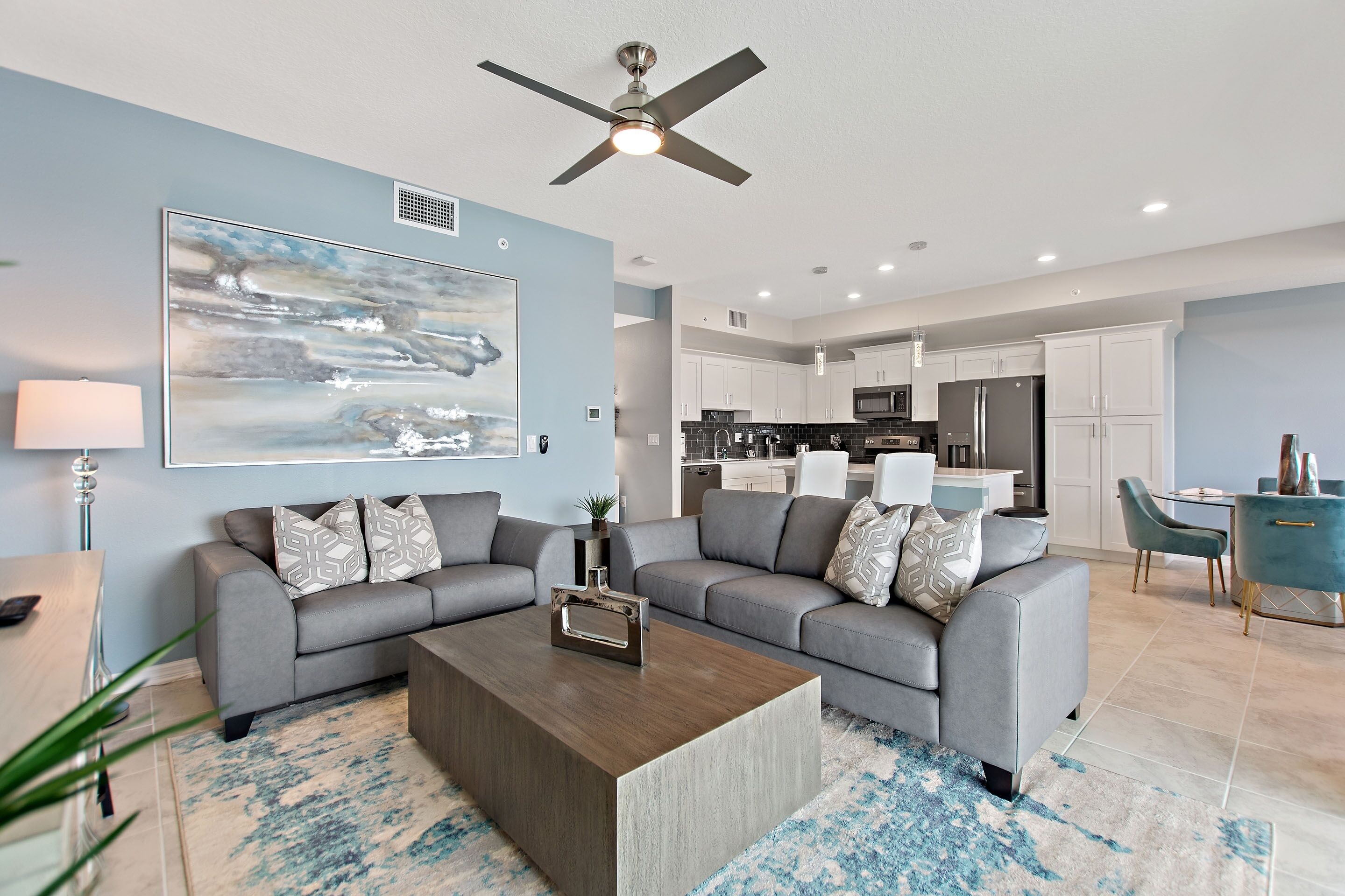 A modern living room with a grey sectional sofa, a coffee table, and a ceiling fan.