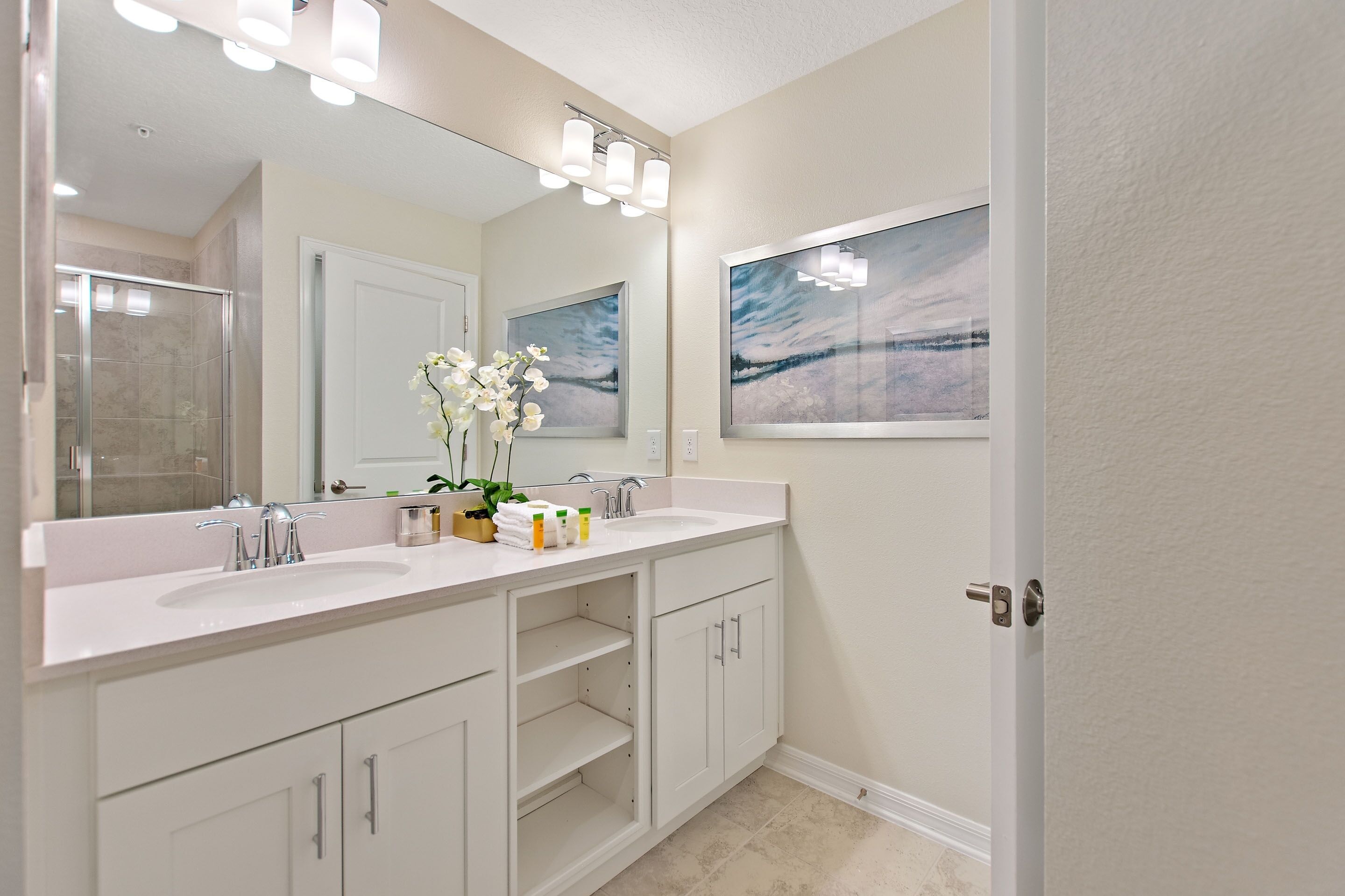 Un bagno con un doppio lavandino, uno specchio grande e un quadro appeso al muro.