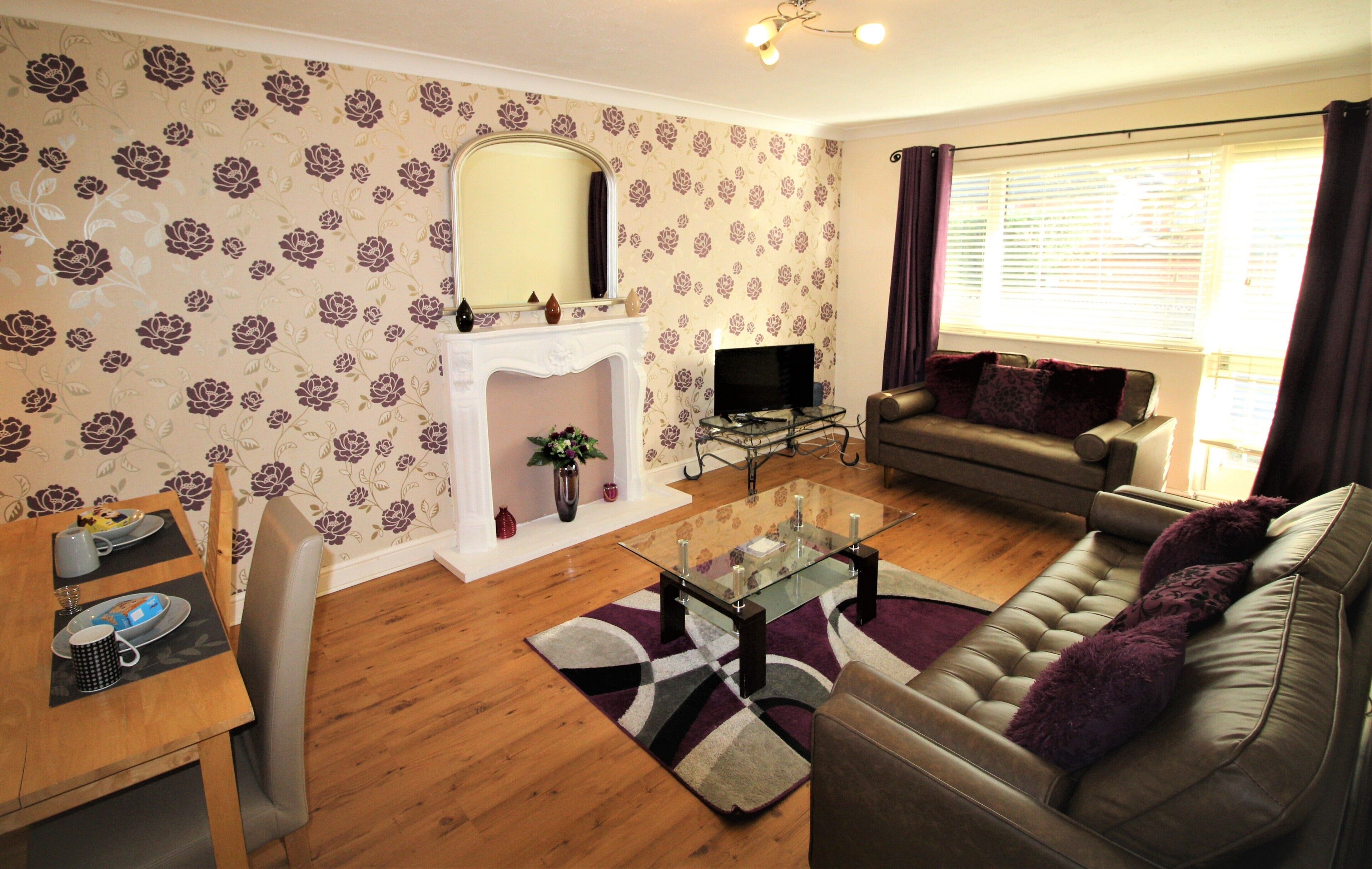 A living room with a sofa, a glass coffee table, a fireplace, and a television.