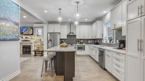 A modern kitchen with white cabinetry, granite countertops, stainless steel appliances, and a central island with bar stools. - Newly Built 5bed home 5 min from DT Portland in Laurelhurst Neighborhood (Portland)
