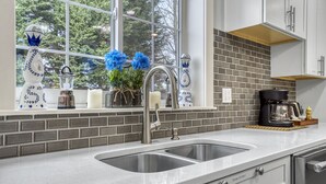 A kitchen with a double sink, a coffee maker, and decorative items on the window sill. - Newly Built 5bed home 5 min from DT Portland in Laurelhurst Neighborhood (Portland)