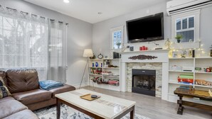 A living room with a leather sofa, a coffee table, a fireplace, a TV, and a bookshelf. - Newly Built 5bed home 5 min from DT Portland in Laurelhurst Neighborhood (Portland)