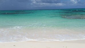 A beach with clear turquoise water and a sandy shore under a partly cloudy sky. - Sand Dollar Cottage 2 Bedroom Cottage (Rock Sound)