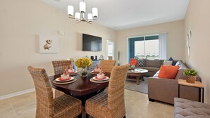 A dining area with a dark wooden table, wicker chairs, and a chandelier. - 3131 Paradox Circle, Unit 404 #838 2 Bedroom Apts (Kissimmee)