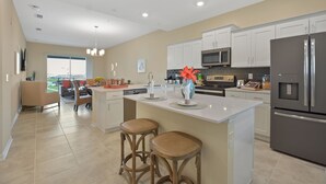 A modern kitchen with white cabinets, stainless steel appliances, and a central island with stools. - 3131 Paradox Circle, Unit 404 #838 2 Bedroom Apts (Kissimmee)