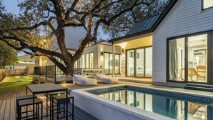 A modern house with a swimming pool, outdoor seating, and a large tree. - 6BDR Luxe Pool Retreat • City Views, Ping Pong, Foosball, Guest House | Henley (Austin)