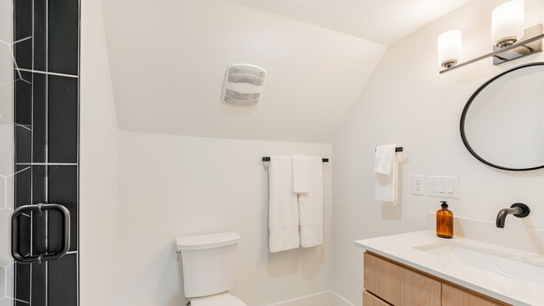 Een moderne badkamer met een wit toilet, een wastafel met spiegel en een handdoekrek.