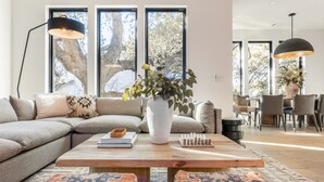 A modern living room with a large sectional sofa, a wooden coffee table, and a chessboard. - 6BDR Luxe Pool Retreat • City Views, Ping Pong, Foosball, Guest House | Henley (Austin)
