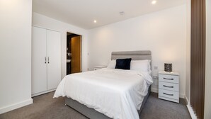 Ein Schlafzimmer mit Bett, Nachttisch, Kleiderschrank und einer Tür zu einem anderen Raum.