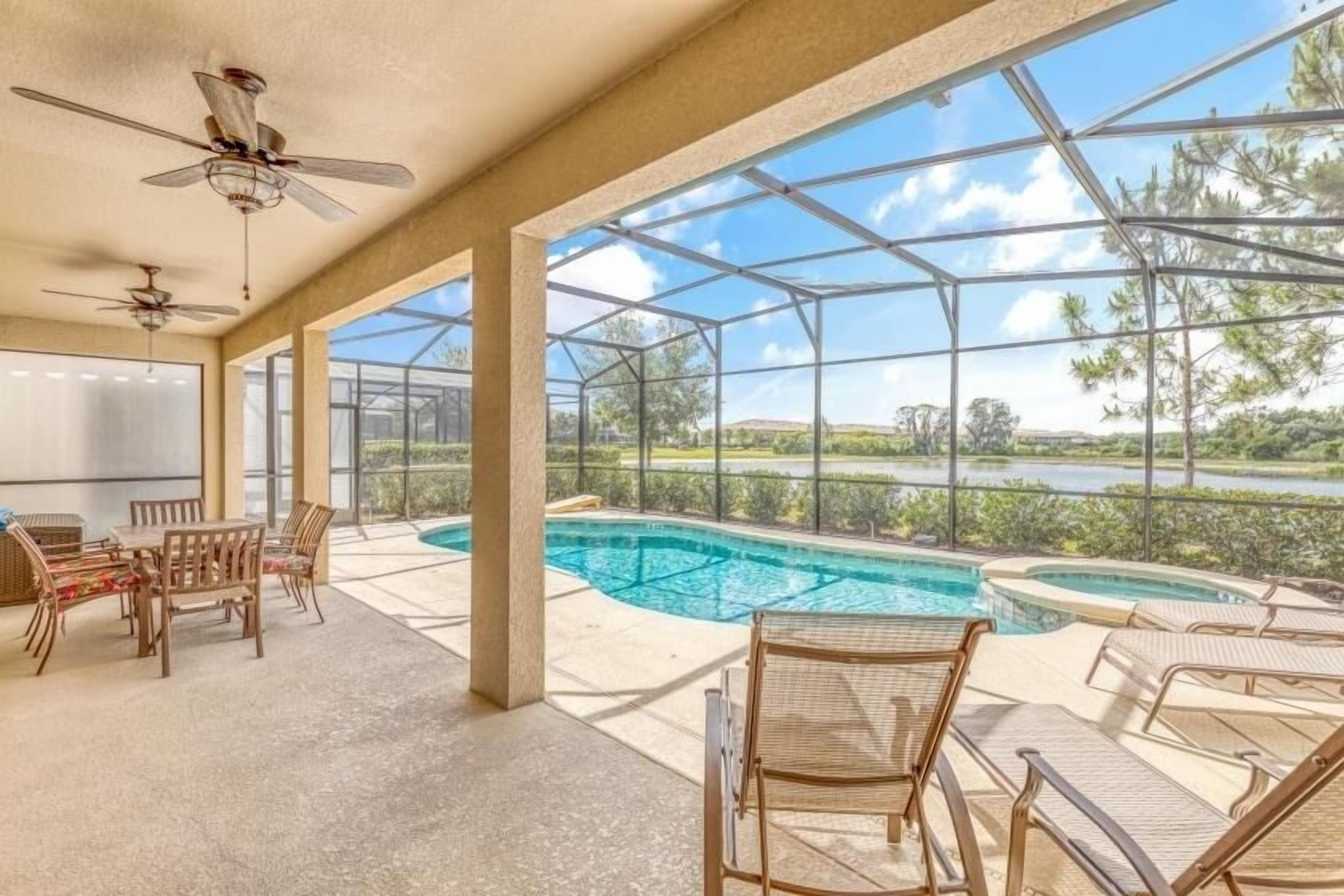 A covered outdoor area with a pool, lounge chairs, and a table with chairs.