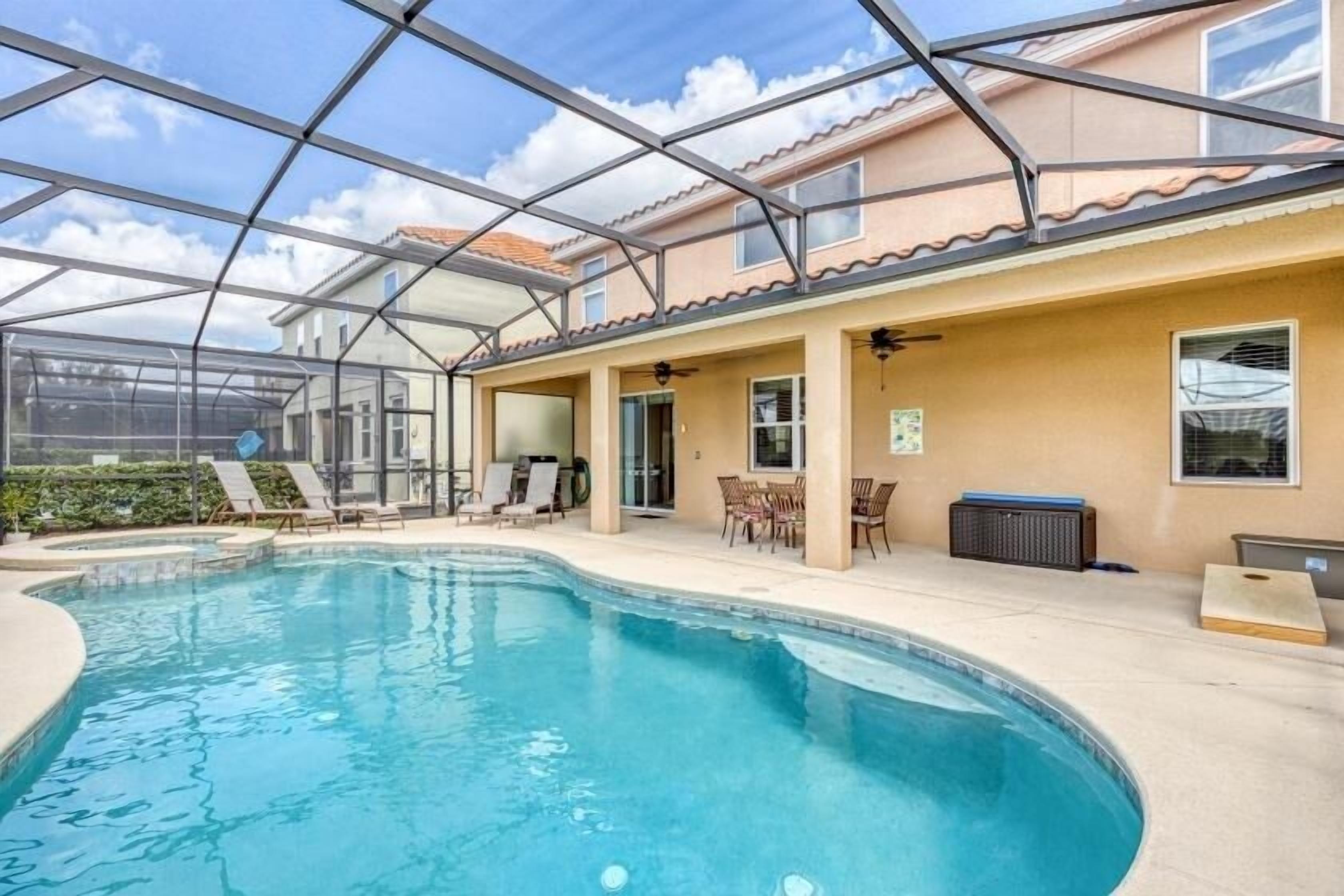 Une piscine entourée de parois en verre, un espace extérieur aménagé avec des sièges et un patio couvert.