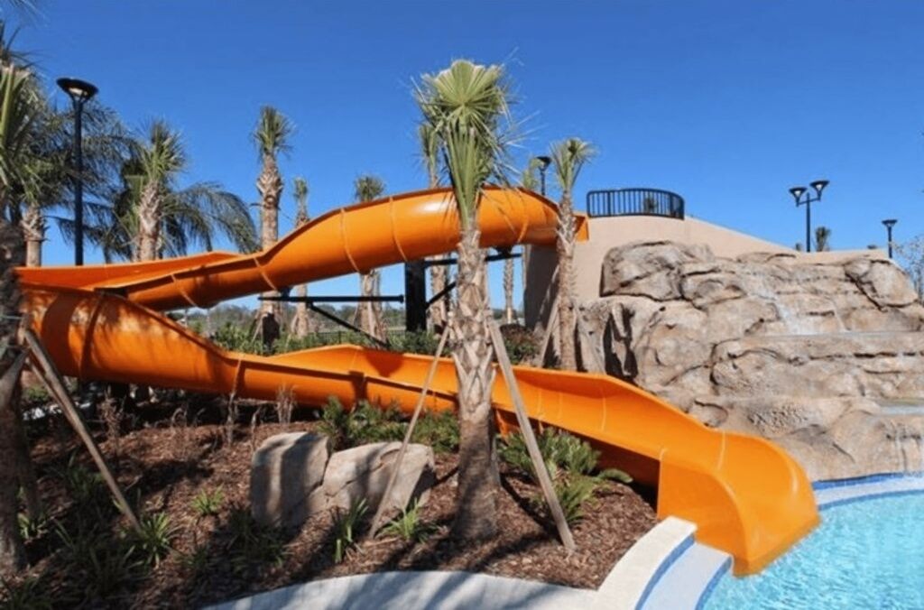 A water park with two orange slides and a pool.