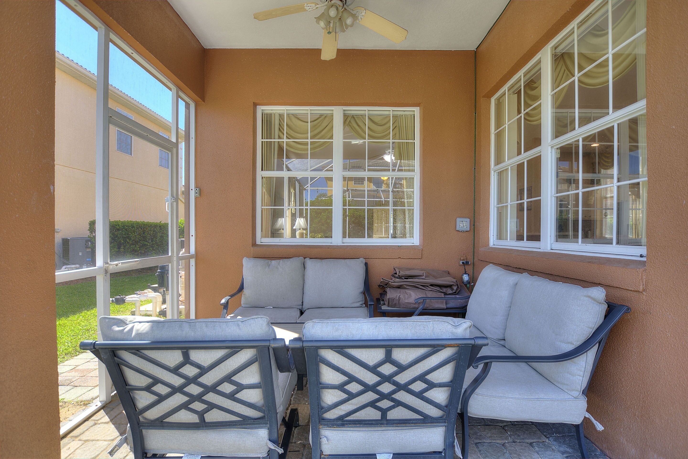 A covered patio area with a ceiling fan, two sofas, and a table.