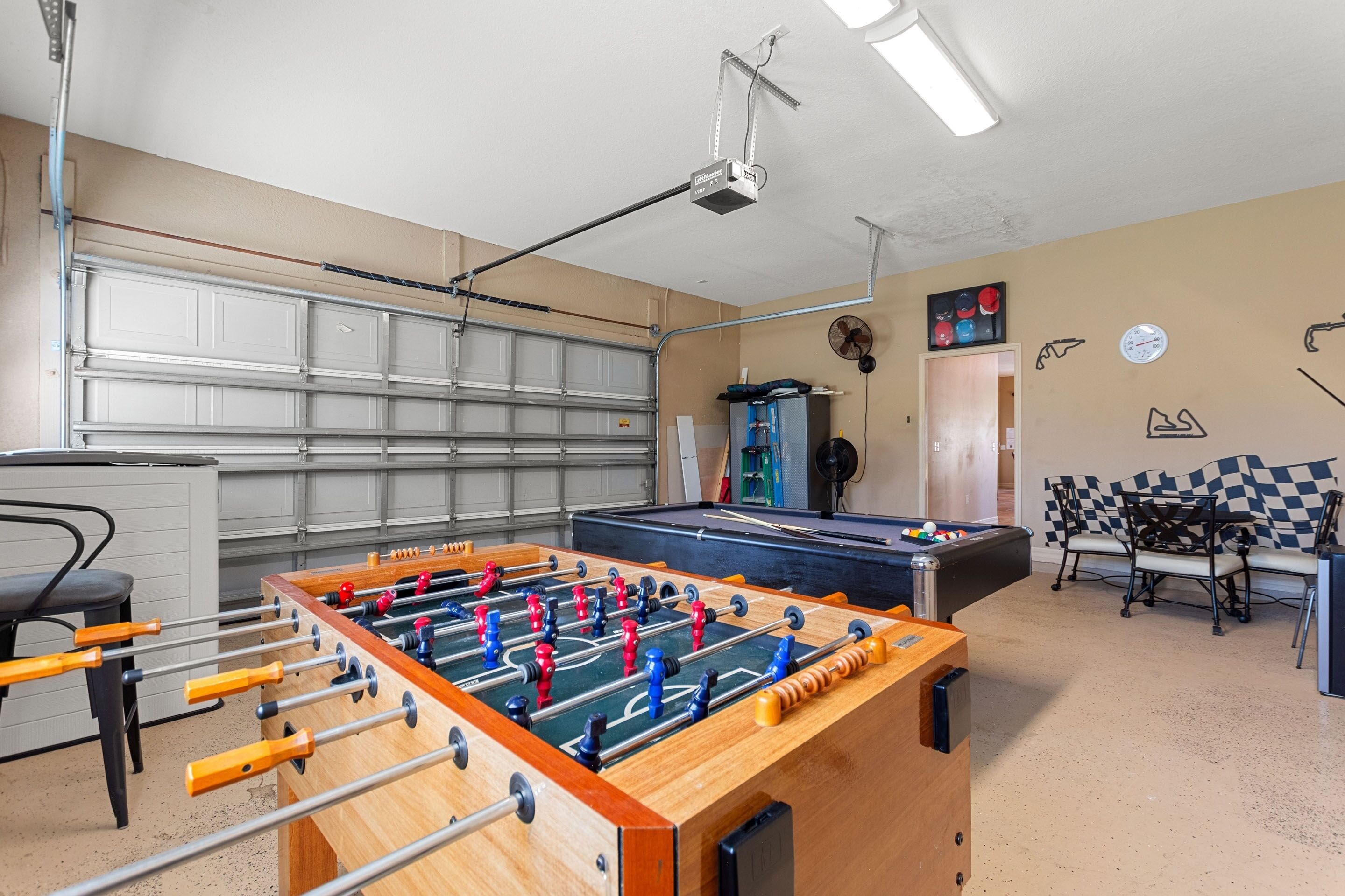 A room with a foosball table, a pool table, and a projector mounted on the ceiling.