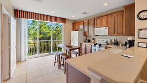 A modern kitchen with wooden cabinets, a large island, and a view of the outdoors. - Vista Cay Resort, Next To Universal 821 3 Bedroom Townhouse (Orlando)
