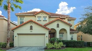 Une maison d’habitation à deux étages, avec une façade beige, un toit recouvert de tuiles rouges et un garage.