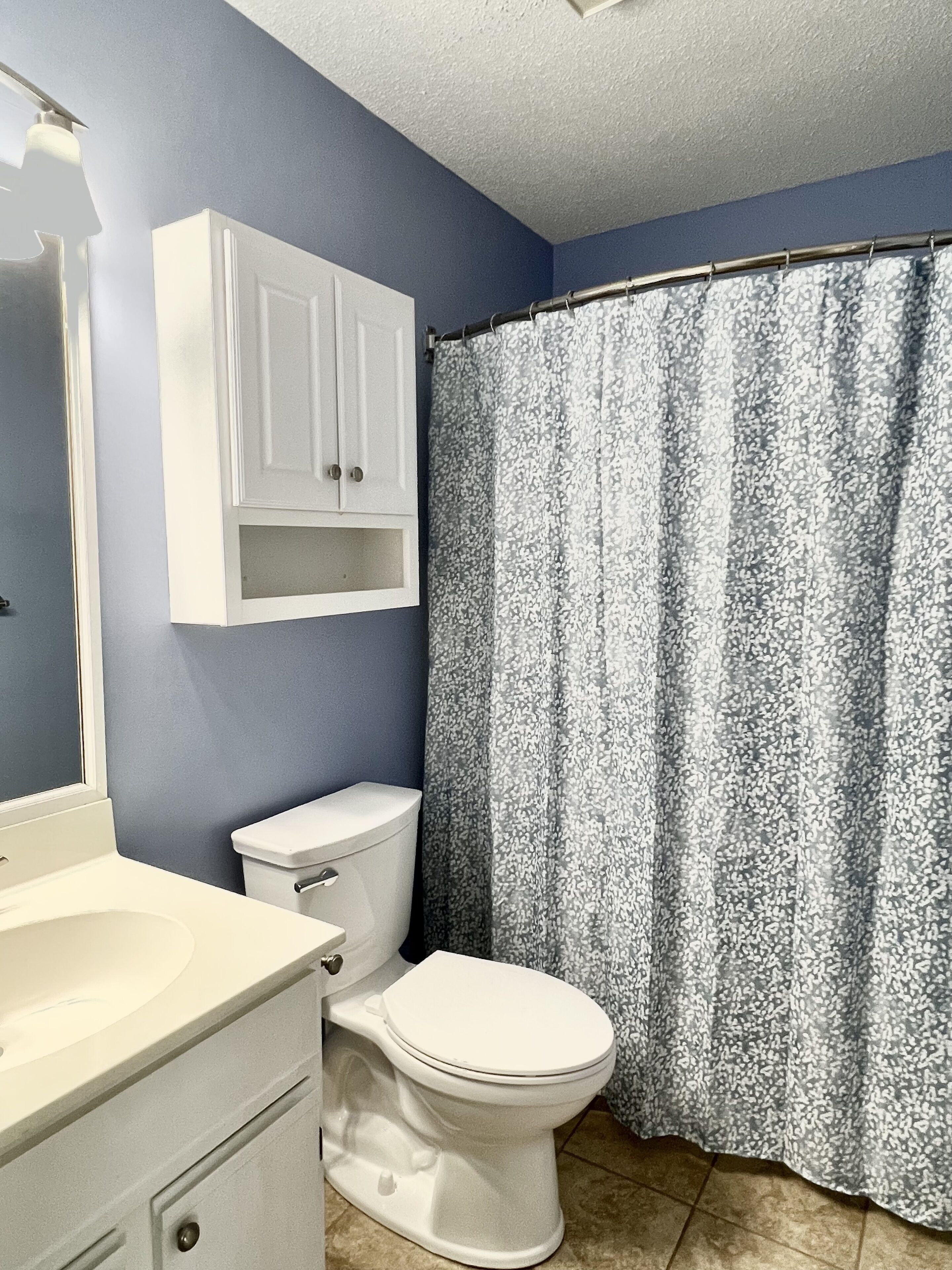 A bathroom with a toilet, a sink, and a cabinet.