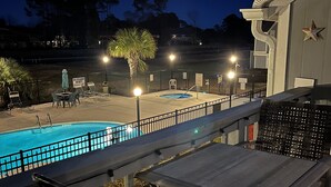 A poolside area with a pool, chairs, and a table.