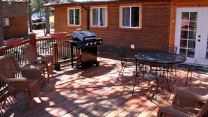 A wooden cabin with a deck, outdoor seating, and a grill. - Mountain Pine Cabin With Personal Hot Tub - Dog-friendly! 3 Bedroom Cabin - #20-NCD0296 (Estes Park)