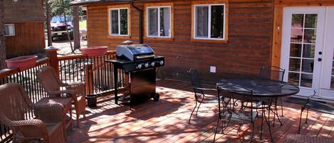 Une cabane en bois dotée d’une terrasse, d’un espace salon extérieur et d’un barbecue.