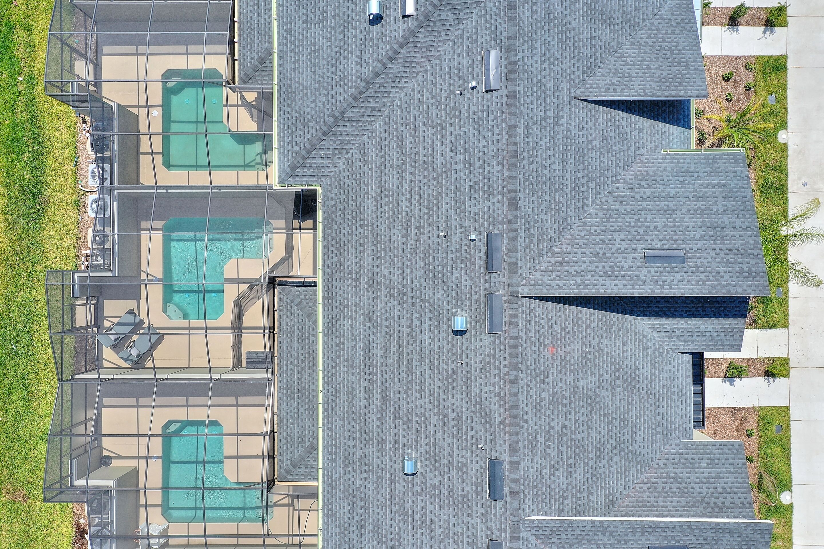 An aerial view of a building with three swimming pools, a covered patio area, and a rooftop with a unique geometric design.
