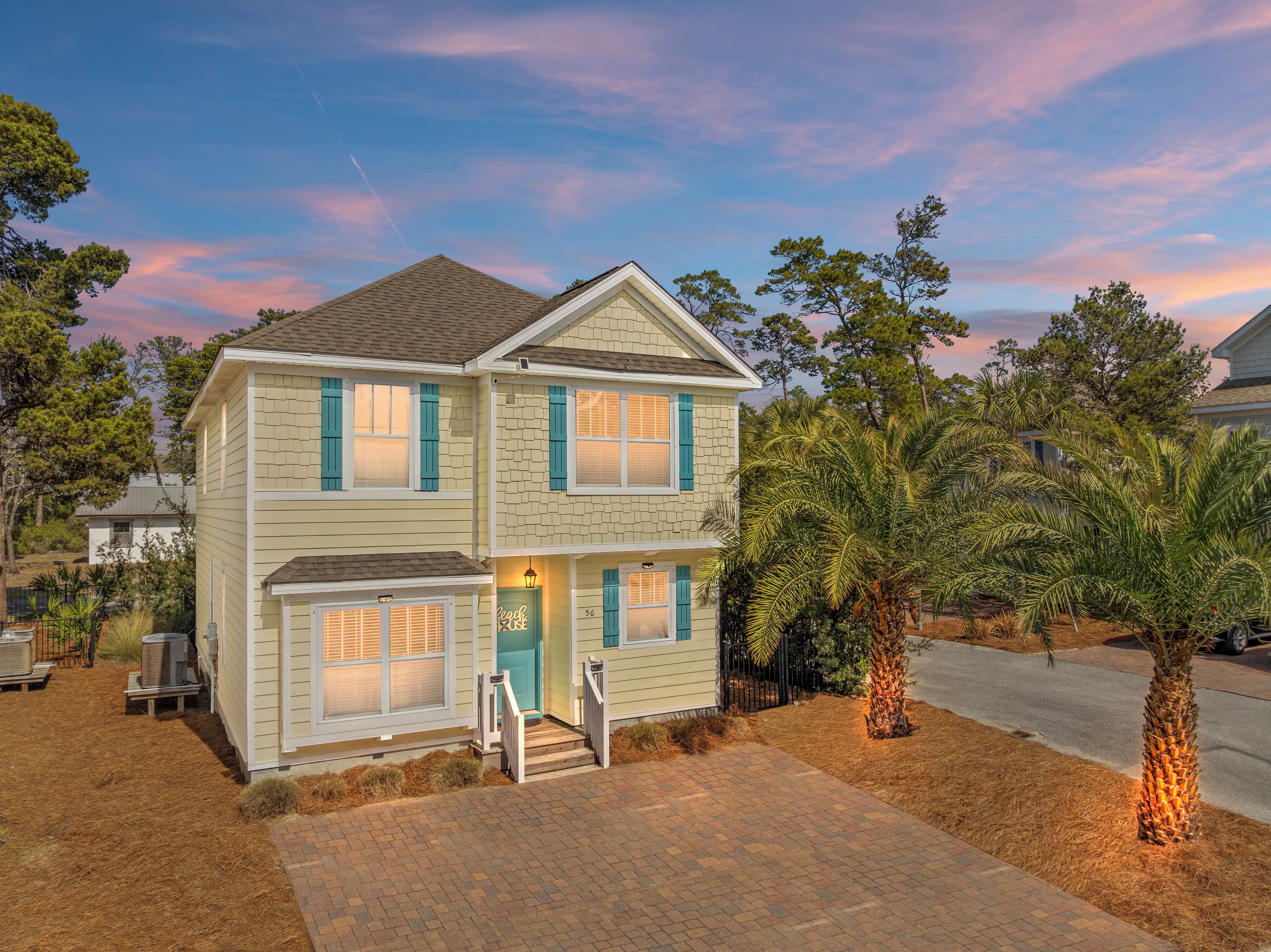 A two-story house with a brick facade, blue shutters, and a front porch with steps.