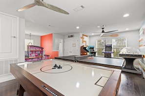 A room with a foosball table, a pool table, and a pinball machine. - The FUN Orange Home in a Great Location With Bonus Game Room (Panama City Beach)