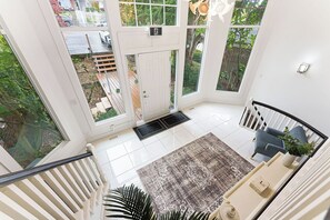 A spacious room with a large window, a door, a staircase, and a seating area with a rug.