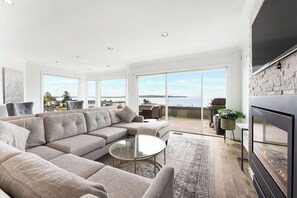 A modern living room with a sectional sofa, a glass coffee table, and a large TV.