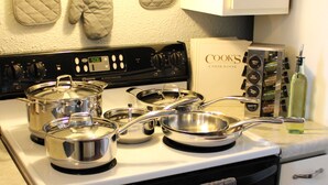 Una cocina con estufa, ollas, sartenes y un libro de cocina.