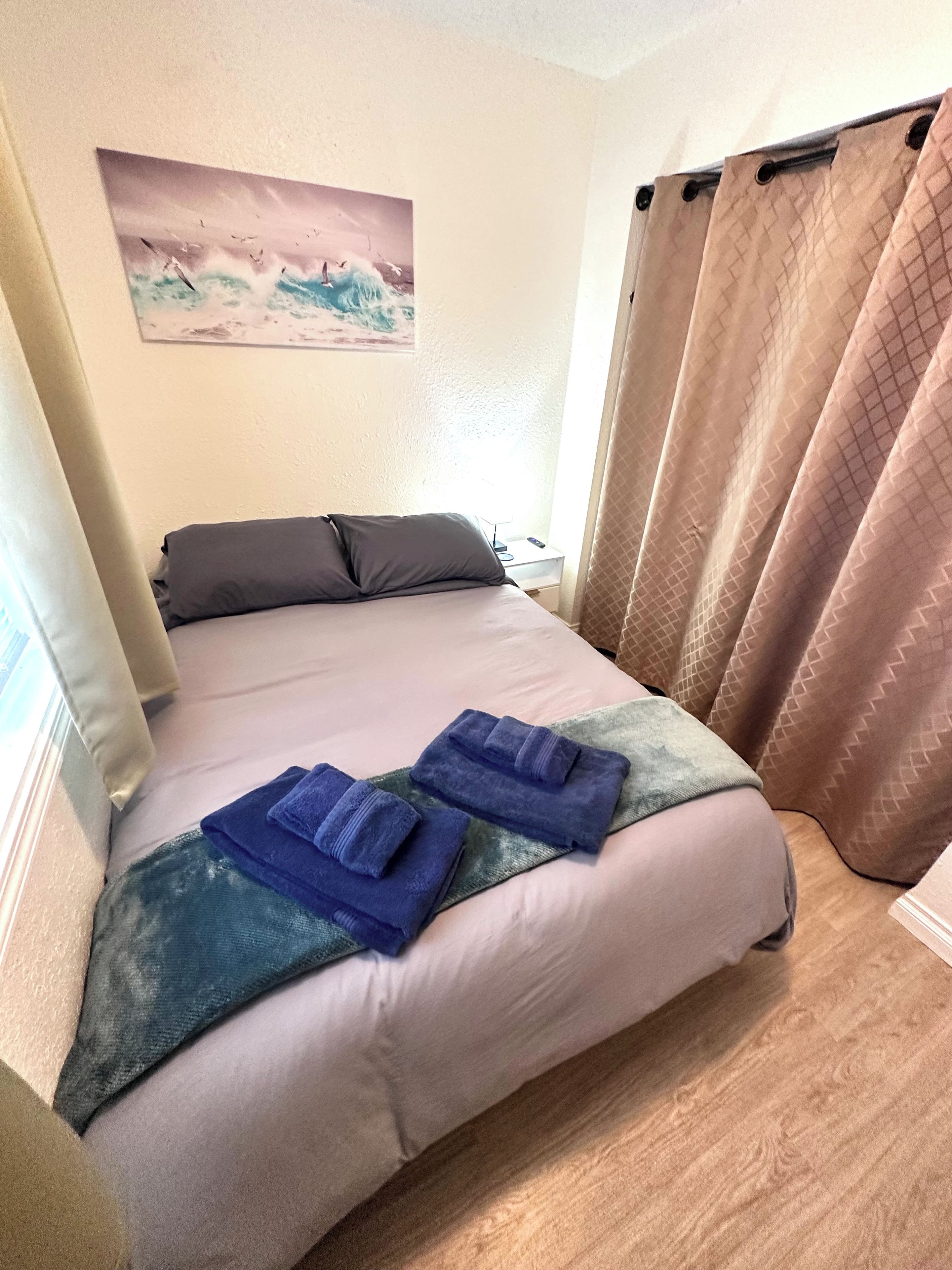 A bed with a pillow, a blanket, and two folded towels.