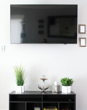 A flat-screen TV mounted on a wall above a black entertainment unit.