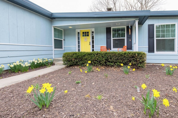A building with a blue exterior, a yellow door, and a front porch with orange chairs. - Retro home in downtown sister bay-Sleeps 6! (Sister Bay)