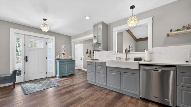A modern kitchen with grey cabinets, a dishwasher, and pendant lighting.