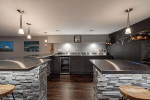 A modern kitchen with a central island, granite countertops, and a stone backsplash. - Stunning home in Downtown Sister Bay-Sleeps 12 (Sister Bay)