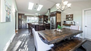 Una cocina amplia con una isla grande, armarios de madera oscura, electrodomésticos de acero inoxidable y una araña.