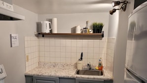 A kitchen with white cabinets, a marble countertop, a sink, and a stove. - Cozy resting place for one (Toronto)