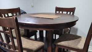 A round wooden dining table with four chairs, each with a woven seat cushion. - Cozy resting place for one (Toronto)