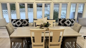 Un comedor con una mesa rectangular y cuatro sillas, cada una con cojín. Hay una planta decorativa sobre la mesa.